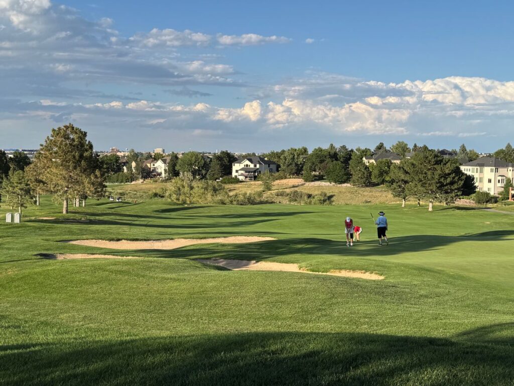 Homes overlooking a Front Range golf course with golfers on the fairway.